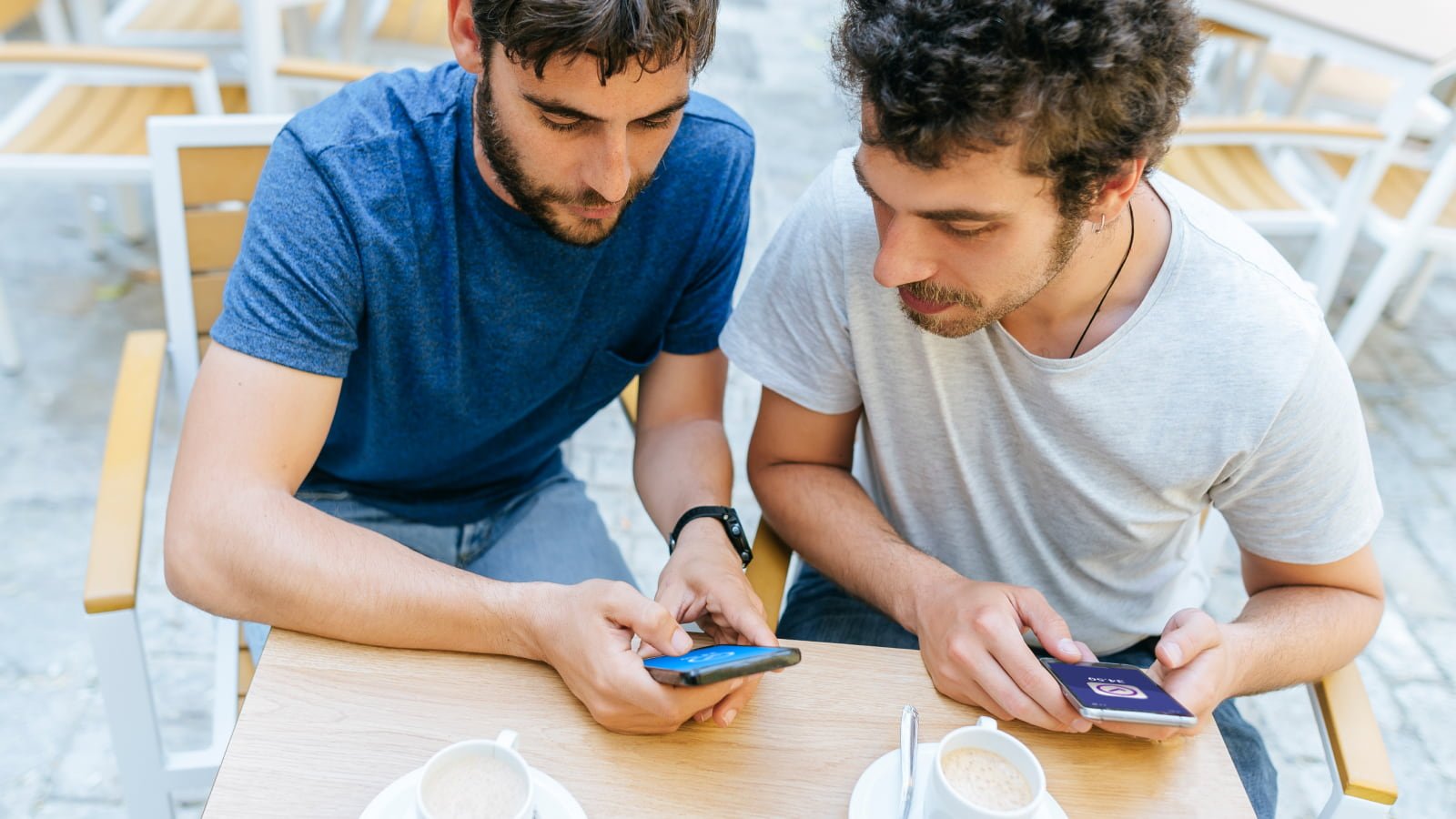 two men at cafe looking at phone